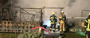 Feuerwehrleute vor den qualmenden Überreste der Gartenlaube.