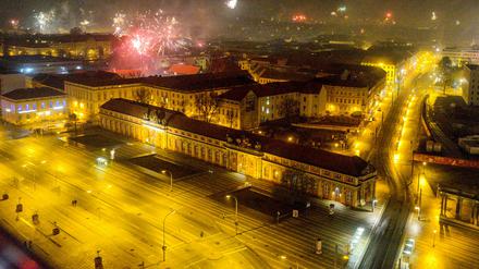 Blick vom Hotel Mercure auf die beleuchtete Breite Straße und das Filmmuseum während in der Silvesternacht Feuerwerk in den Nachthimmel aufsteigt. 