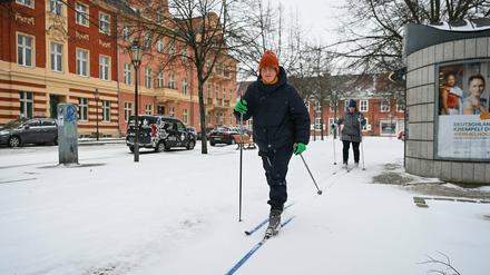Zwei Potsdamerinnen fahren auf Langlauf-Ski über den schneebedeckten Fußweg am Bassinplatz. 