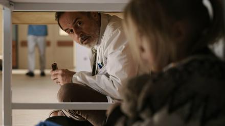 Doktor Ballouz (Merab Ninidze) setzt sich zu Flori (Mavie Meschkowski) unter den Tisch - eine Szene der aus der ZDF-Reihe.