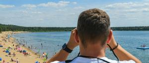 Ein Rettungsschwimmer vom Deutschen Roten Kreuz (DRK) beobachtet die Badegäste im Wasser des Helenesees (Archivfoto).