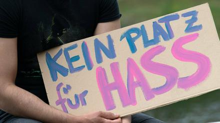 Eine Person hält ein Schild, auf dem steht „Kein Platz für Hass“.