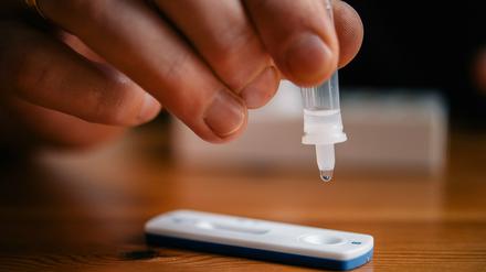 Ein Mann träufelt eine Lösung auf eine Testkassette, die von Covid-19 verursachte Antigene nachweisen kann (Symbolbild).