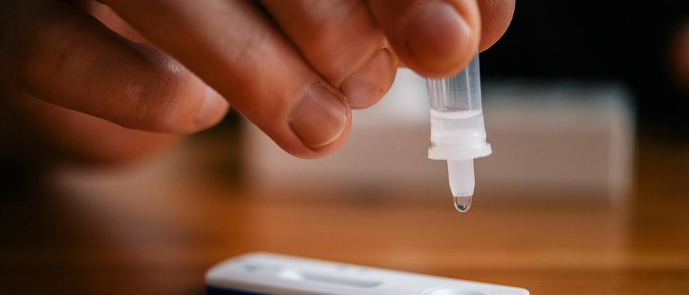 Ein Mann träufelt eine Lösung auf eine Testkassette, die von Covid-19 verursachte Antigene nachweisen kann (Symbolbild).