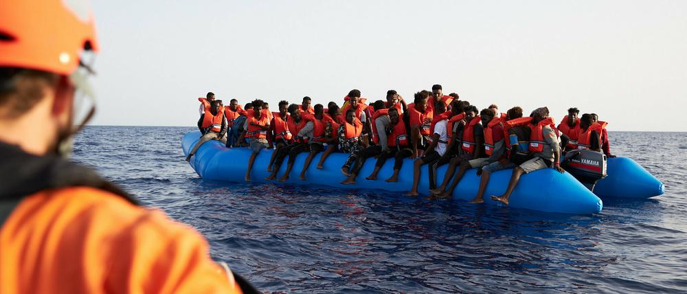 Die von der Seenotrettungsorganisation Sea-Eye herausgegebene Aufnahme zeigt einen Seenotretter, der zu einem Flüchtlingsboot schaut. Potsdam will den Verein nun unterstützen.