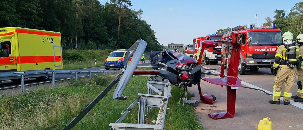 Einsatzkräfte der Feuerwehr stehen an der Absturzstelle eines Tragschraubers am Autobahndreieck Nuthetal. 