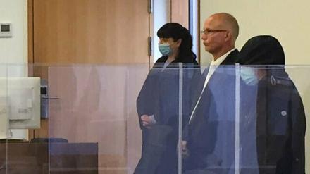 Ines R. (r, mit dunkler Kapuze) wegen Mordes und versuchten Mordes angeklagt.
