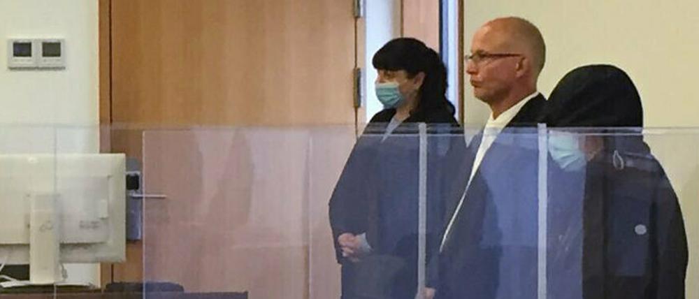 Ines R. (r, mit dunkler Kapuze) wegen Mordes und versuchten Mordes angeklagt.