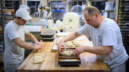 Bäcker Guido Marzillier (r.), stellvertretender Backstubenleiter in der Bäckerei und Konditorei Plentz, und Bäcker Benjamin Fischer formen mit den Händen den Teig für Marzipanstollen.
