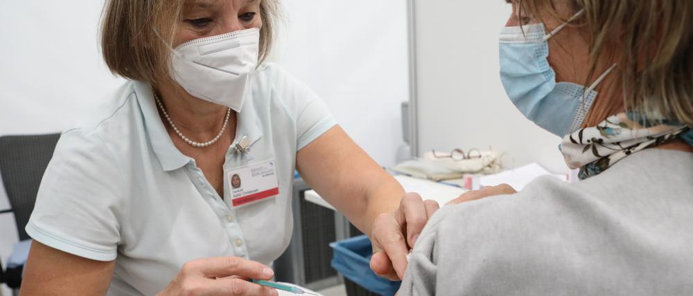 Eine Fachärztin beim Impfen einer älteren Person.