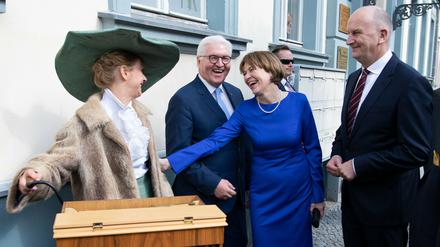 Bundespräsident Frank-Walter Steinmeier, seine Frau Elke Büdenbender und Brandenburgs Ministerpräsident Dietmar Woidke (SPD, r.) unterhalten sich zur Eröffnung des Fontanejahres 2019 bei einem Stadtrundgang in Neuruppin mit einer Drehorgelspielerin.