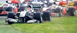 Durch die Wiese. Schon in der ersten Kurve krachte es: Jenson Button (links) initiierte den Crash, bei dem sich Michael Schumacher (vorn) die Nase krumm fuhr. Foto: dpa