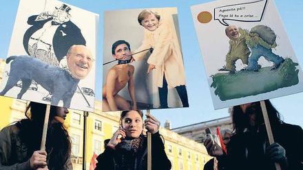 Wut: Demonstranten zeigen auf ihren Protesttafeln, in welchen Rollen sie die deutsche Bundeskanzlerin Angela Merkel und den portugiesischen Ministerpräsidenten Pedro Passos Coelho sehen. Foto: picture alliance/dpa