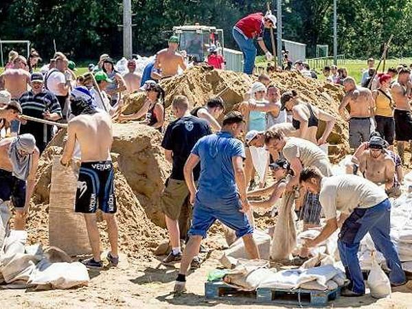 Menschen schaufeln Sand und füllen Sandsäcke