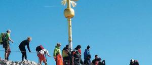 Ansturm auf die Zugspitze. Die Menschen drängeln sich am Gipfelkreuz. 