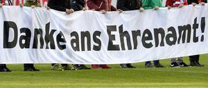Ehrenamtliche Mitarbeiter halten ein Plakat im Stadion des SC Freiburg.