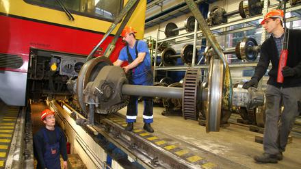 Mitarbeiter reparieren die Achsen eines S-Bahn-Wagens.