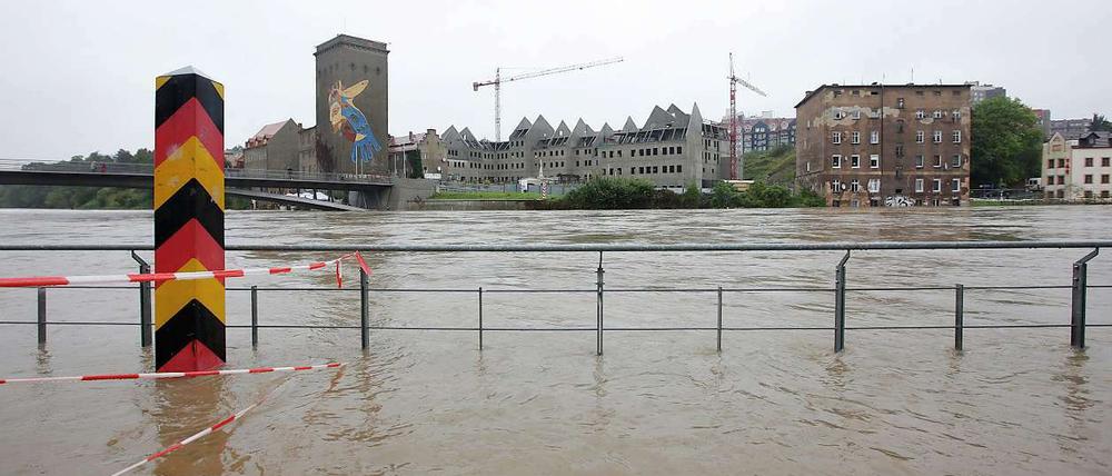 Ein Grenzpfahl steht am Dienstag im deutsch-polnischen Grenzfluss Neiße. Im Hintergrund ist die polnische Stadt Zgorzelec zu erkennen. Trotz nachlassenden Regens in einigen Teilen desLandes ist die Hochwassersituation in Ostsachsen weiter angespannt. Im Landkreis Görlitz herrscht weiterhin Katastrophenalarm.