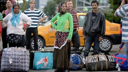 Rumänische Roma blicken am Flughafen in Bukarest zu Journalisten, nachdem sie mit mehr als 200 weiteren aus Frankreich kommenden Roma dort eingetroffen sind. 