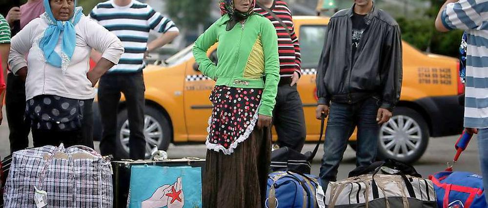 Rumänische Roma blicken am Flughafen in Bukarest zu Journalisten, nachdem sie mit mehr als 200 weiteren aus Frankreich kommenden Roma dort eingetroffen sind. 