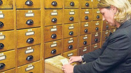 Die Last der Geschichte. Das Document Center wurde von der US-Regierung in der ehemaligen Preußischen Hauptkadettenanstalt in Lichterfelde untergebracht, die zuvor Standort der SS-Leibstandarte Adolf Hitler war. Auf dem Foto hält eine Mitarbeiterin die Mitgliedskarte Adolf Hitlers aus dem NSDAP-Archiv in der Hand. 