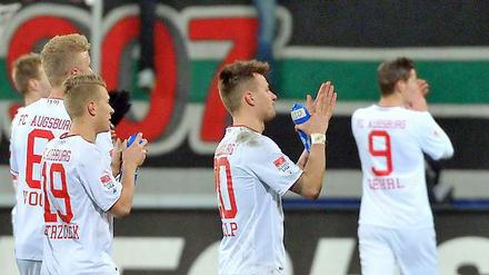 Erlaubtes Eigenlob . Die Augsburger Spieler beklatschen sich und die FCA-Fans.