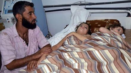 Ein Mann sitzt neben zwei Kindern in einem syrischen Krankenhaus, die nach Angaben von Aktivisten bei einem Giftgaseinsatz der Armee verletzt worden sein sollen.