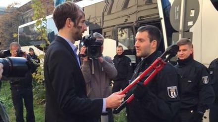Philipp Ruch, künstlerischer Leiter der Gruppe „Zentrum für Politische Schönheit“, und Bundespolizisten vor der Abfahrt der Reisebusse.