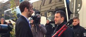 Philipp Ruch, künstlerischer Leiter der Gruppe „Zentrum für Politische Schönheit“, und Bundespolizisten vor der Abfahrt der Reisebusse.
