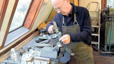Mit dem Hammer signiert. Lutz Werner schlägt sein Siegel in den Boden eines Baumkerzenhalters. 