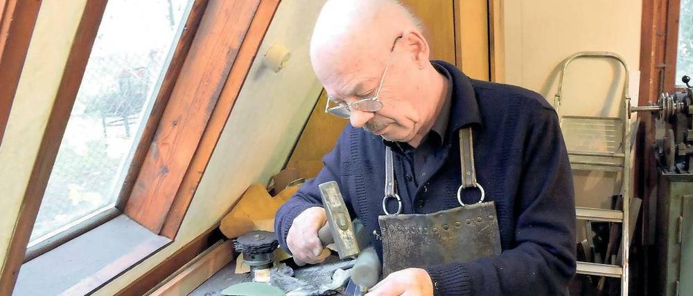Mit dem Hammer signiert. Lutz Werner schlägt sein Siegel in den Boden eines Baumkerzenhalters.
