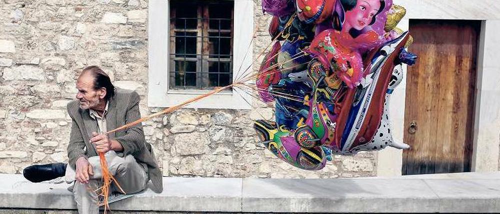 Jeder Cent zählt. Ein Mann in Athen möchte Luftballons an Urlauber verkaufen.