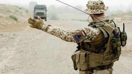 Ein Soldat der Bundeswehr weist wenige Kilometer westlich von Kundus in Afghanistan während eines Einsatzes an einer Straßensperrung einem Lkw den Weg.