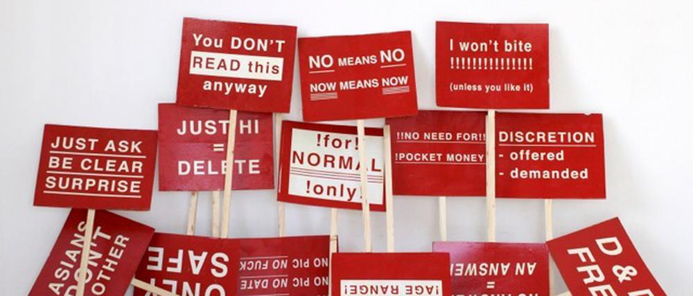 Gedruckte Protestschilder mit typischen Online-Dating-Regeln.