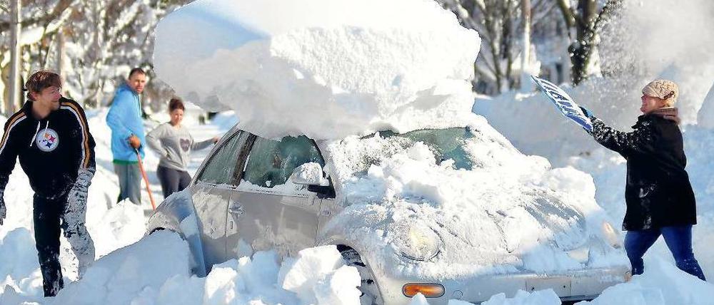 Kunst am Schnee. Diese Menschen in Hamburg, einem Vorort von Buffalo, räumen ihr Auto frei. Viele Menschen starben, weil sie von den Schneemassen eingeschlossen wurden.