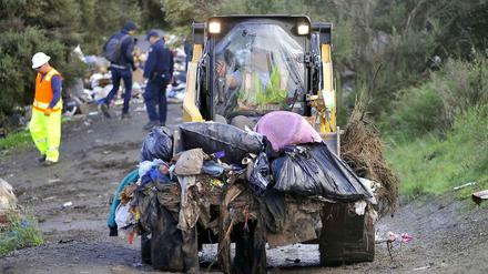 Ein Bulldozer räumt die Reste der Behausungen und Müll ab.