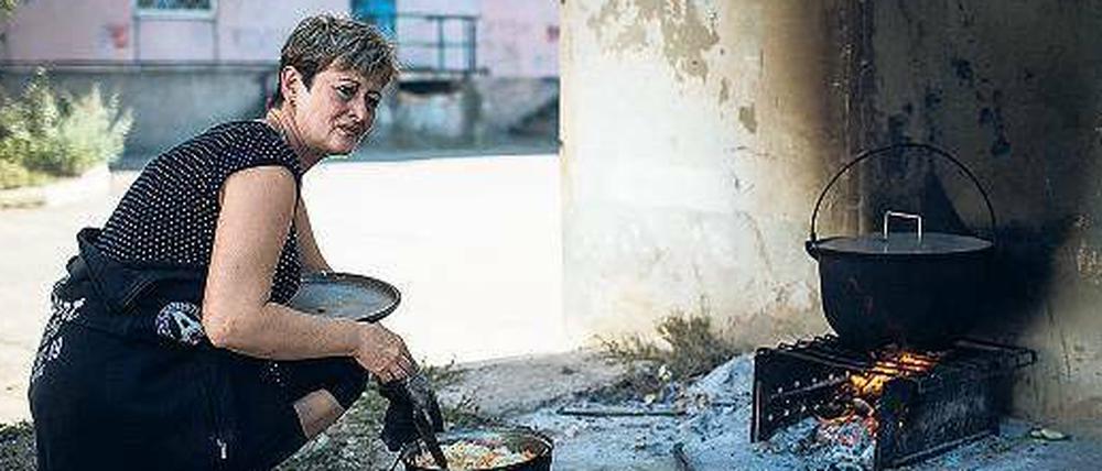 Die Lebensbedingungen werden immer härter. Eine Frau muss vor der Tür über offenem Feuer kochen.