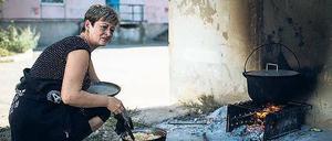 Die Lebensbedingungen werden immer härter. Eine Frau muss vor der Tür über offenem Feuer kochen.