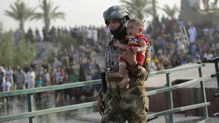 Ein irakischer Soldat bringt ein Kind in Ramadi in Sicherheit.