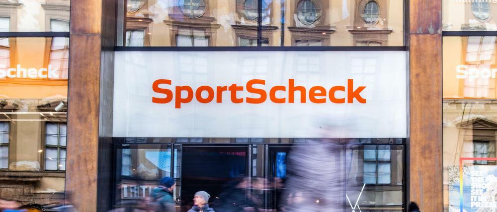 Personen gehen an einer Sportscheck-Filiale in der Münchener Fußgängerzone vorbei.