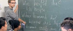 Ein studentischer Deutschlehrer steht an der Tafel, junge Männer und Frauen schauen auf Schriftzüge wie "Woher kommst du".