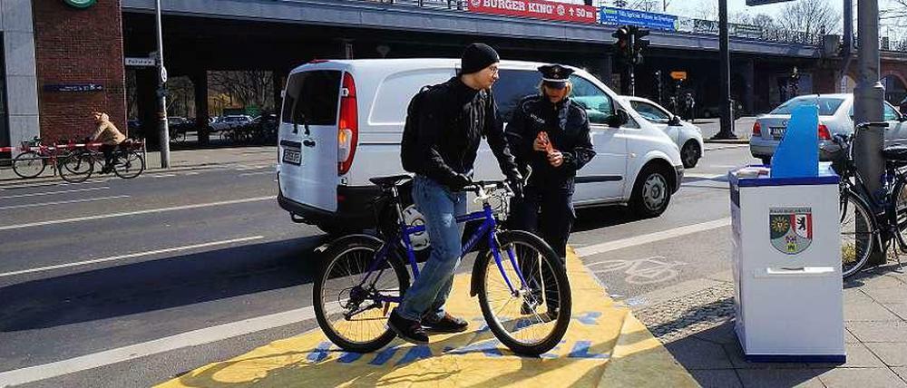 Vorsicht, Toter Winkel! Die Polizistin am S-Bahnhof Tiergarten erklärt einem Radler anhand der gelben Plane, welchen Bereich viele Lkw-Fahrer beim Rechtsabbiegen nicht sehen.