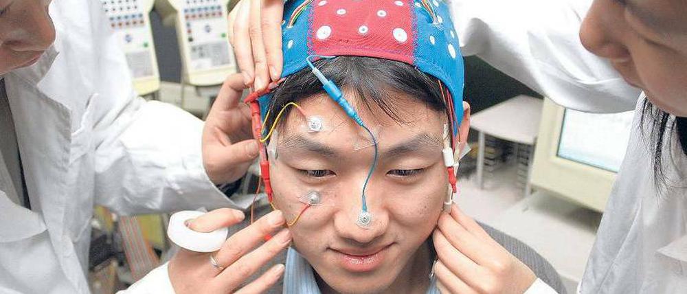 Voll verkabelt. Wissenschaftler der nordchinesischen Universität Tianjin bereiten ein Experiment vor, bei dem es um Informationsaustausch zwischen menschlichem Gehirn und Computer geht.  