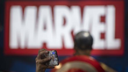 Ein Besucher einer Messe in Hongkong macht ein Foto vor einem Marvel-Logo.