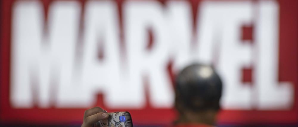 Ein Besucher einer Messe in Hongkong macht ein Foto vor einem Marvel-Logo.