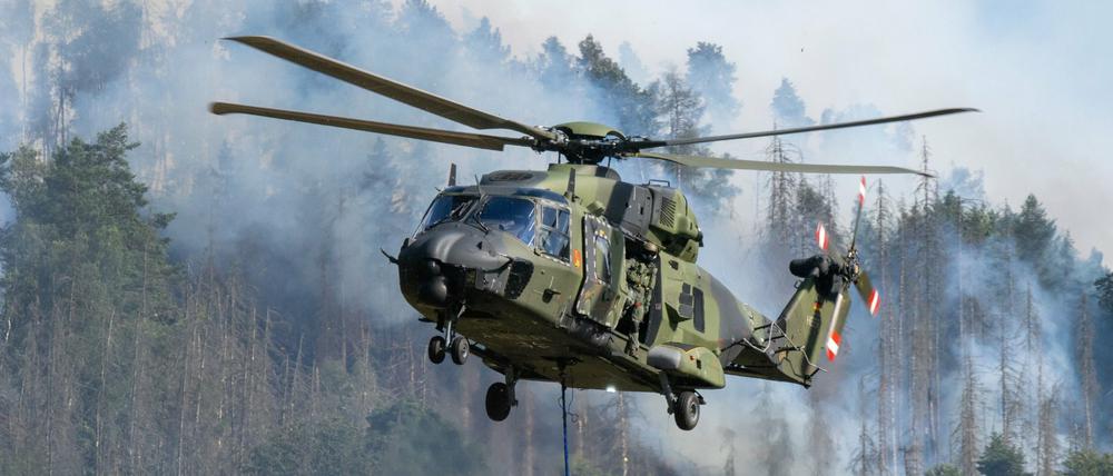 Hubschrauber der Bundeswehr fliegen mit einem Löschwasser-Außenlastbehälter über die Brände im Nationalpark Sächsische Schweiz.