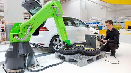 Ein junger Mann arbeitet an einer Montagestation eines Automobilherstellers.