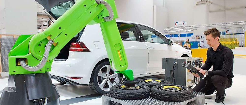 Ein junger Mann arbeitet an einer Montagestation eines Automobilherstellers.