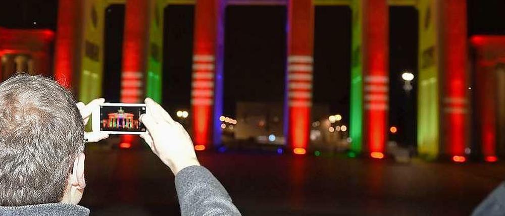 Der Regierende demonstriert: Um das für Olympia angestrahlte Brandenburger Tor zu fotografieren, ist ein Handy durchaus hilfreich - für die Olympia-Umfrage allerdings nicht. 