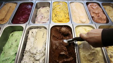 Ein Mensch holt eine Eiskugel aus den Eisbechern.